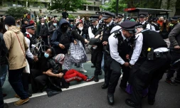 Des policiers arrĂȘtent des manifestants rassemblĂ©s autour d'un bus en attente de transporter des migrants et des demandeurs d'asile d'un hĂŽtel de Peckham, au sud de Londres, vers la barge Bibby Stockholm Ă Portland, dans le Dorset, au sud-ouest de l'Angleterre, le 2 mai 2024