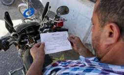 Un Syrien lit un tract portant le sceau des forces gouvernementales et appelant la population à "rejoindre le (processus de) réconciliation" à Binnish, dans le nord-ouest de la Syrie, le 9 août 2018