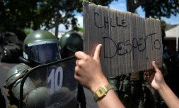 Un manifestant brandit une pancarte proclamant "le Chili s'est réveillé" devant les forces de l'ordre, au cinquiÚme jour d'une violente contestation sociale, le 22 octobre 2019 à Santiago