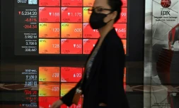 Une femme passe devant les écrans de la Bourse de Jakarta le 9 mars 2020, "lundi noir" qui a vu les bourses mondiales plonger 