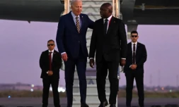 Le président américain Joe Biden (g) marche à côté du ministre angolais des Affaires étrangères Tete Antonio à son arrivée à l'aéroport international Quatro de Fevereiro de Luanda, le 2 décembre 2024