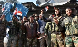 Des soldats du régime agitent des drapeaux syriens avec le portrait d'Assad dans le quartier de Bab al-Nairab à Alep le 10 décembre 2016