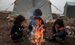 Des enfants autour d'un feu dans un camp de déplacés, dans le nord-ouest de la Syrie, le 17 décembre 2021