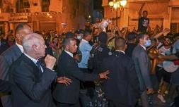 Une photo fournie par la présidence tunisienne montre le chef de l'Etat Kais Saied (G) levant le poing droit pour célébrer avec ses partisans à Tunis la victoire quasi certaine du "oui" au référendum sur une Constitution contestée, le 26 juillet 2022
