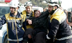 Des membres de la Défense civile syrienne aident une femme déplacée ayant fui les quartiers kurdes d'Alep, encerclés par l'armée, le 8 janvier 2026