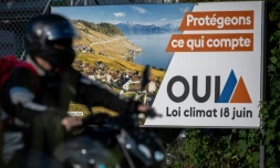Un motard passe devant une affiche électorale indiquant "Protégeons ce qui compte, OUI, loi climat 18 juin" à Lausanne, en Suisse, le 14 juin 2023