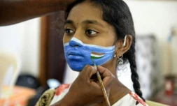 Un artiste peint un masque sur le visage d'une jeune fille lors d'une campagne de sensibilisation au Covid-19 à Hyderabad (Inde) le 20 septembre 2020