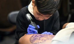 Napat Mitmakorn, 9 ans, travaille sur le tatouage de son oncle lors de la 2025 Thailand Tattoo Expo à Bangkok, le 15 mars 2025 en Thaïlande