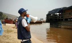 Mégaphone à la main, Yves Matwa, agent de la riposte à Ebola, passe les consignes aux passagers d’une baleinière, au port de Bende-Bende, commune de Maluku, à 70 km au nord-est de Kinshasa, le 20 août 2026