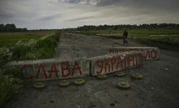 Un civil passe en vélo un barrage routuer sur lequel est écrit "Gloire à l'Ukraine" près de Barvinkove, dans le Donbass, dans l'est de l'Ukraine, le 29 mai 2022