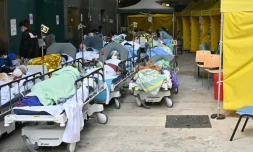 Des patients attendent sur des lits  devant le centre médical Caritas, le 15 février 2022 à Hong Kong où le nombre de contaminations au Covid-19 a grimpé en flèche