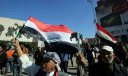 Des Irakiens brandissent le drapeau national lors de la parade militaire pour célébrer la victoire militaire contre le groupe Etat islamique (EI), à Bagdad