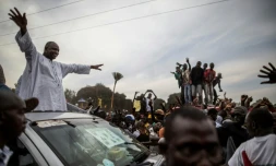 Adama Barrow, porte-drapeau de la coalition des sept partis politiques d'opposition en Gambie, salue les partisans du toit de sa voiture lors d'un rassemblement dans la zone tampon de Talinding le 29 novembre 2016