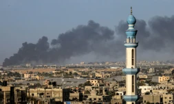 Une photo prise de Rafah montrant un nuage de fumée s'élevant le 22 janvier 2024 au dessus de Khan YounÚs dans le sud de Gaza aprÚs des combats entre l'armée israélienne et le groupe islamiste palestinien du Hamas