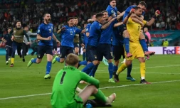 Le gardien de but italien Gianluigi Donnarumma, félicité par ses coéquipiers, après avoir repoussé le pénalty du milieu de terrain anglais Bukayo Saka, lors des tirs au but, offrant la victoire (1-1, 3-2 t.a.b.) à la Squadra Azurra, le 11 juillet 2021 au stade de Wembley à Londres