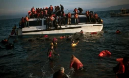 Des migrants quittent leur bateau en train de sombrer le 30 octobre 2015 sur le rivage de l'île de Lesbos en Grèce