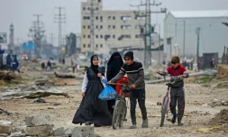 Des jeunes Palestiniens marchent autour des décombres dans le camp de réfugiés de Maghazi, dans le centre de la bande de Gaza, en partie détruit par les bombardemebnts israéliens, le 27 février 2024