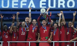L'attaquant vedette du Portugal Cristiano Ronaldo (c) brandit le trophée entouré des ses équipiers après la victoire face à la France en finale de l'Euro au Stade de France, le 10 juillet 2016