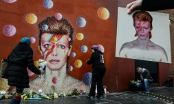 Des fans déposent des fleurs en hommage au chanteur David Bowie, après l'annonce de son décès, devant une fresque à son effigie, de l'artiste de rue australien James Cochran, dans le quartier de Brixton, à Londres, le 11 janvier 2016.