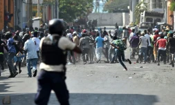Un policier vise des manifestants avec une arme, lors de violents affrontements à Port-au-Prince, le 13 février 2019 en Haïti