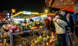 Un survivant blessé (à droite) enlace un proche près d'un mémorial improvisé après un incendie dans un bar qui a fait 40 morts et plus de 100 blessés au nouvel an, à Crans-Montana (Suisse) le 2 janvier 2026