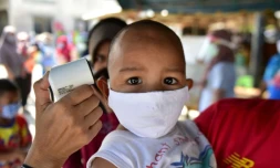 Vérification de la température d'un enfant, masqué, en Thaïlande dans la cadre de la prévention du Covid-19, le 17 avril 2020