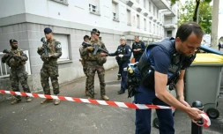 Un policier municipal installe un ruban de police alors que des militaires de l'opération "Sentinelle" sont présents devant le lycée de Nantes où une lycéenne a été tuée et trois autres blessés à coups de couteau par un élève, le 24 avril 2025 