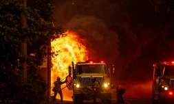 Un pompier sauve un drapeau américain des flammes qui consument une habitation de Greenville, en Californie, le 4 août 2021