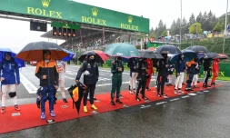 Des pilotes attendent sous la pluie sur la ligne de départ du GP de F1 de Belgique menacé par le mauvais temps, le 29 août 2021 à Spa-Francorchamps 