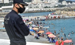 Un policier masqué surveille la plage El Kettani à Bab El Oued prÚs d'Alger, le 15 août 2020