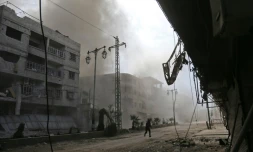 De la fumée et de la poussiÚre s'élÚvent d'une rue aprÚs des raids aériens du régime syrien sur la localité de Hammourié, dans le fief rebelle de la Ghouta orientale prÚs de Damas, le 21 février 2018
