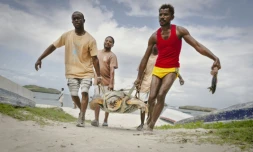Des pêcheurs qui ont hameçonnée une tortue aident des membres de l'ONG Local Ocean Conservation (LOC) à la transporter vers le centre du LOC où elle sera soignée, le 22 mai 2025 à Watamu, au Kenya