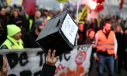 Un homme tient une caisse pour soutenir les grévistes, dans une manifestation à Paris le 26 décembre 2019