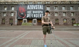 Le soldat ukrainien Vladyslav Jaïvoronok du régiment Azov, amputé d'une jambe, devant une affiche géante "Libérez les défenseurs de Marioupol", le 16 août 2022 à Kiev