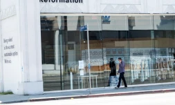 Une personne portant un masque passe devant un magasin fermé sur l'avenue Melrose à Los Angeles, le 3 août 2020