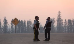 Des policiers entourés d'une épaisse fumée bloquent l'accès à Fort McMurray, le 6 mai 2016