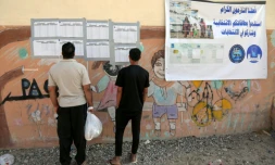Des Irakiens déplacés consultent les listes nominatives affichées à l'extérieur d'un bureau de vote, à l'arrivée pour voter avant les élections législatives du 11 novembre, dans un camp du nord de l'Irak, le 9 novembre 2025
