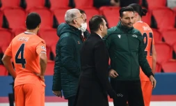 L'entraîneur de l'Istanbul Basaksehir, Okan Buruk (g), discute avec le 4e arbitre roumain Sebastian Coltescu (d) après l'interruption du match de groupes de la Ligue des champions contre le Paris-SG, au Parc des Princes, le 8 décembre 2020