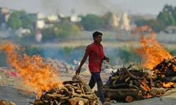 Un homme marche entre les bûchers d'un crématorium à Allahabad, en Inde, le 27 avril 2021