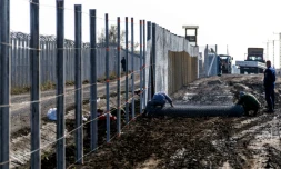 Des détenus érigent une clôture à la frontière hongro-serbe dans le village de Gara, le 27 octobre 2016, destinée à empêcher des migrants d'entrer en Hongrie