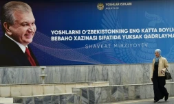 Une femme passe le 20 octobre 2021 à Tachkent devant une affiche de campagne du président de l'Ouzbékistan Chavkat Mirzioïev, réélu dimanche