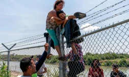 Nataly Barrionuevo, son fils dans les bras, escalade une clĂŽture de barbelĂ©s aprĂšs avoir traversĂ© le Rio Grande du cĂŽtĂ© mexicain et ĂȘtre entrĂ© aux Etats-Unis Ă Eagle Pass, au Texas, le 25 aoĂ»t 2023