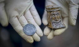 Lara Maiklem, une "mudlark" (littéralement "fouilleuse de boue"), montre une pièce du XVIIe siècle et un morceau d'une carafe en pierre qu'elle a trouvés sur les rives du fleuve Thames à Londres, le 29 mai 2019.