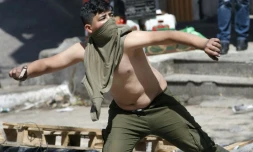 Un manifestant palestinien jette des pierres sur des soldats israéliens le 31 mars 2018 à Hébron, en Cisjordanie