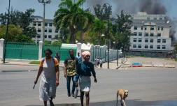De la fumée s'échappe d'un bùtiment du ministÚre des Finances, alors que des habitants quittent les lieux aprÚs avoir entendu des tirs, le 2 avril 2024 à Port-au-Prince, en Haïti