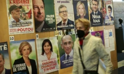 Une femme passe devant les affiches Ă©lectorales des candidats Ă la prĂ©sidentielle, prĂšs du lycĂ©e français Ă New York oĂč des Ă©lecteurs commençaient Ă voter, le 9 avril 2022