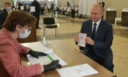Le président russe Vladimir Poutine montre son passeport à un assesseur avant de voter à Moscou, le 1er juillet 2020.