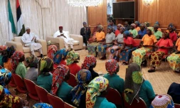 Une photo diffusée par PGDBA&HND Mass Communication montre le président nigérian Muhammadu Buhari (g) qui accueille 82 lycéennes de Chibok libérées à Abuja, le 7 mai 2017