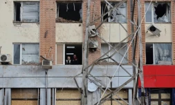 Des habitants regardent Ă travers la fenĂȘtre d'un bĂątiment endommagĂ© aprĂšs un bombardement Ă MykolaĂŻv, le 19 avril 2022