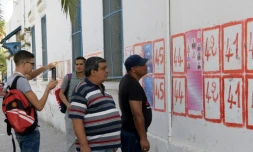 Des Tunisiens regardent des listes de candidats aux élections collées à un mur de la capitale Tunis, le 14 septembre 2019